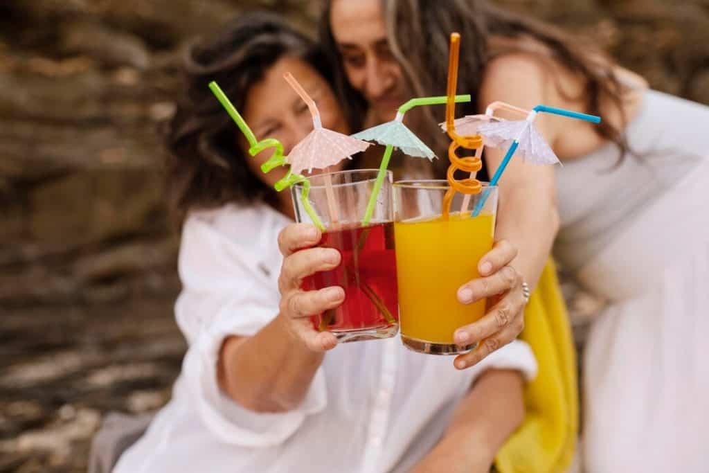 senior female friends cheering with cocktails beach 23 2149014624
